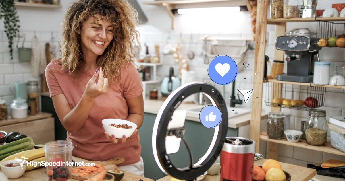 photo of woman blogging in her kitchen with phone set-up on a tripod with simplified social media illustrations: like, love, and share