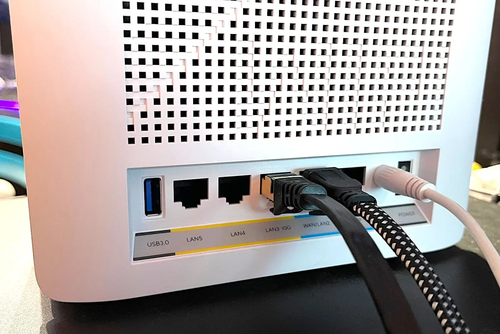 Backside of a mesh router showing Ethernet cables plugged into LAN and WAN ports.