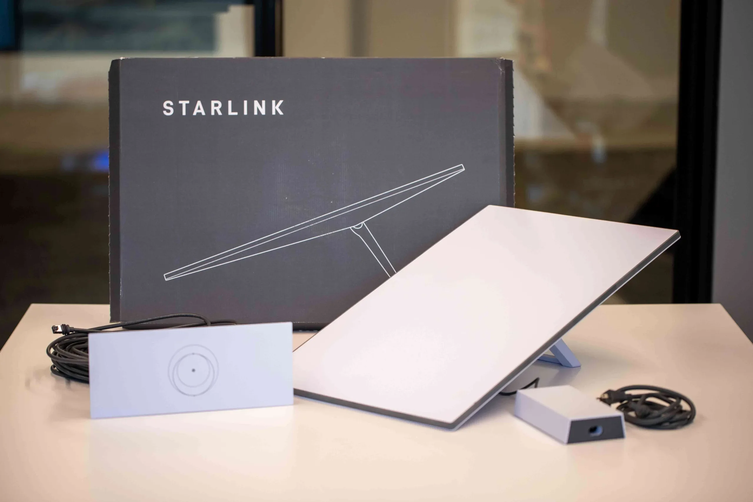 standard Starlink kit unboxed HSI Unboxed Starlink Standard kit, including a receiver dish, Wi-Fi router, power supply, and cables.